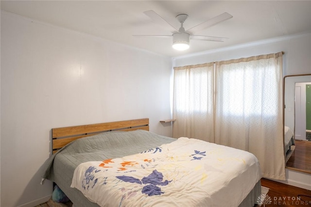 bedroom featuring crown molding, dark wood-type flooring, and ceiling fan