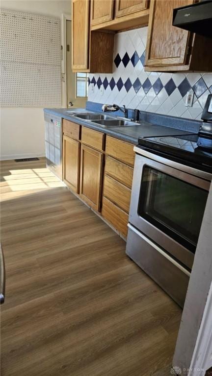 kitchen with sink, electric range, dark hardwood / wood-style flooring, range hood, and backsplash