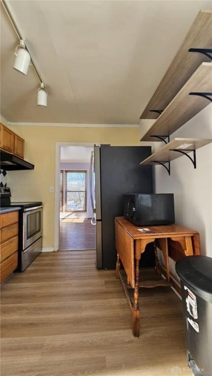 kitchen featuring stainless steel electric range oven, ventilation hood, rail lighting, ornamental molding, and light hardwood / wood-style flooring