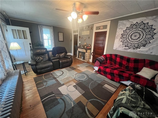 living room with a fireplace, hardwood / wood-style flooring, ceiling fan, and crown molding