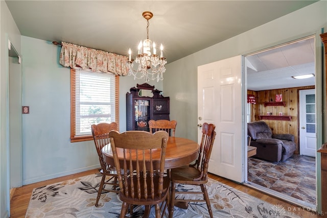 dining area with wood walls, light hardwood / wood-style flooring, and a chandelier