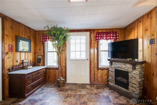 kitchen featuring a stone fireplace and wooden walls