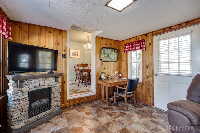 office featuring a fireplace, an inviting chandelier, and wood walls