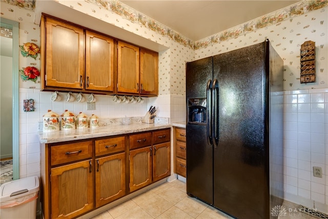 kitchen featuring light tile patterned floors, black fridge, tile walls, and light stone counters