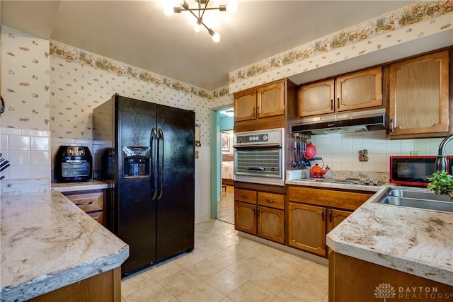 kitchen featuring black fridge, white cooktop, sink, light tile patterned floors, and oven