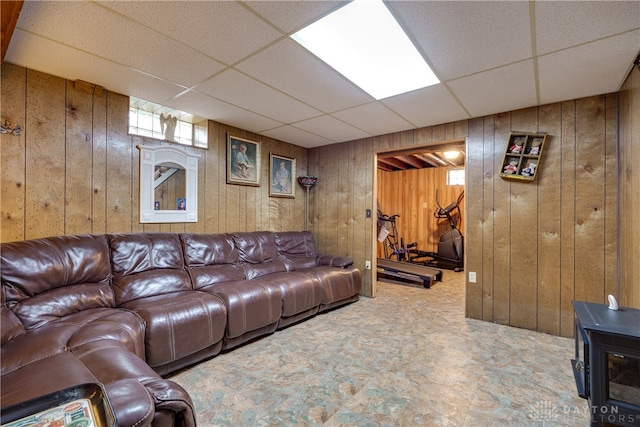 living room with a paneled ceiling and wood walls