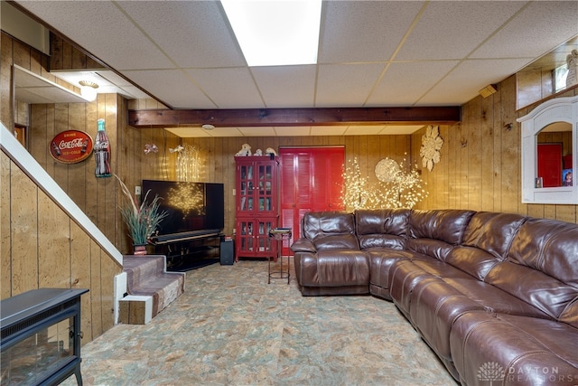 living room featuring a drop ceiling and wooden walls