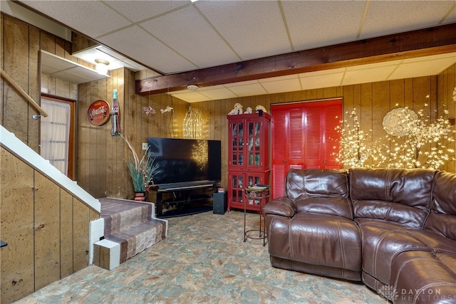 living room featuring a drop ceiling and wooden walls