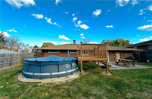 rear view of house featuring a lawn and a pool side deck