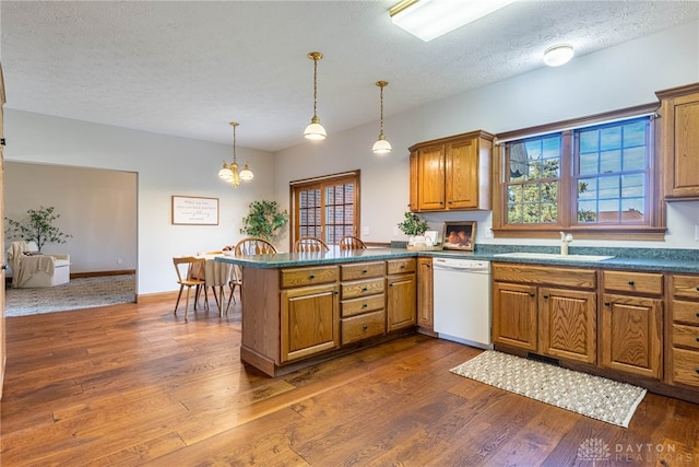 kitchen featuring dark wood-type flooring, white dishwasher, kitchen peninsula, a textured ceiling, and pendant lighting