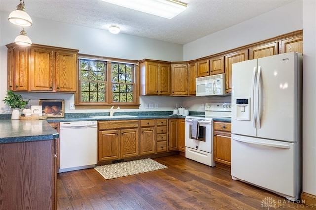 kitchen with a textured ceiling, sink, dark hardwood / wood-style floors, pendant lighting, and white appliances