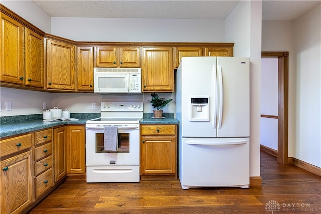 kitchen with dark wood-type flooring, white appliances, and a textured ceiling