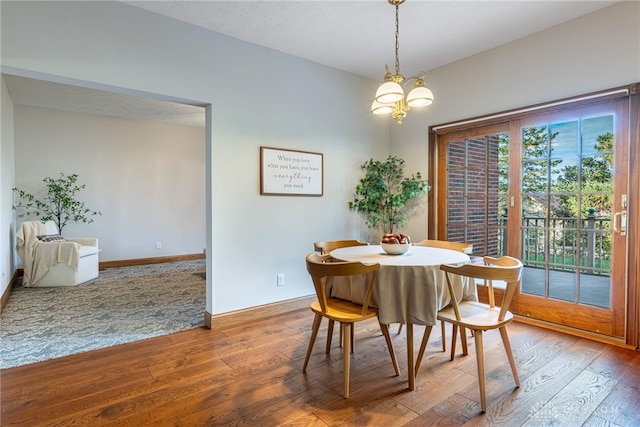 dining space with wood-type flooring, a textured ceiling, and an inviting chandelier