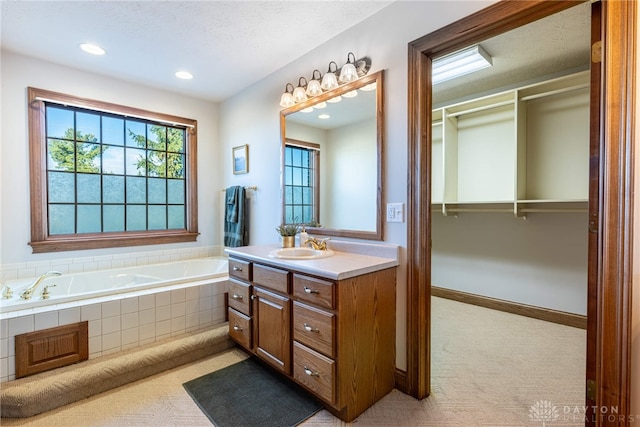 bathroom featuring tiled bath, vanity, and a textured ceiling