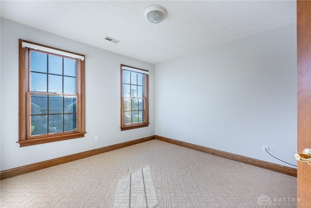 carpeted empty room featuring a textured ceiling