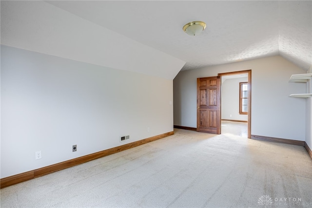 bonus room featuring light colored carpet, a textured ceiling, and lofted ceiling