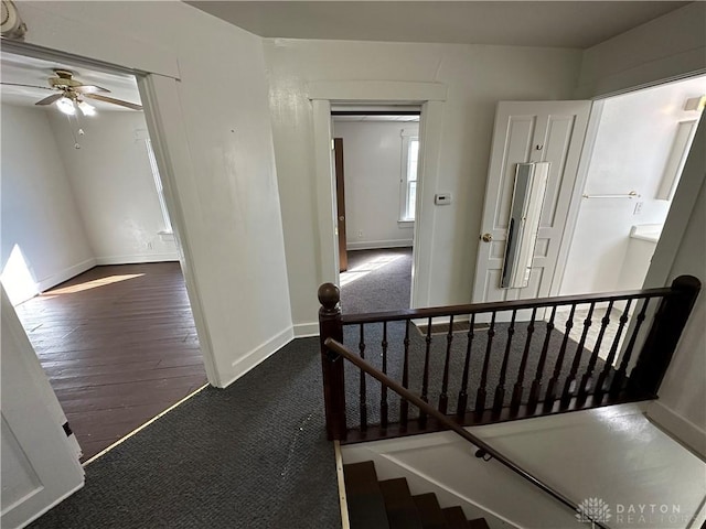 corridor featuring dark wood finished floors, an upstairs landing, and baseboards