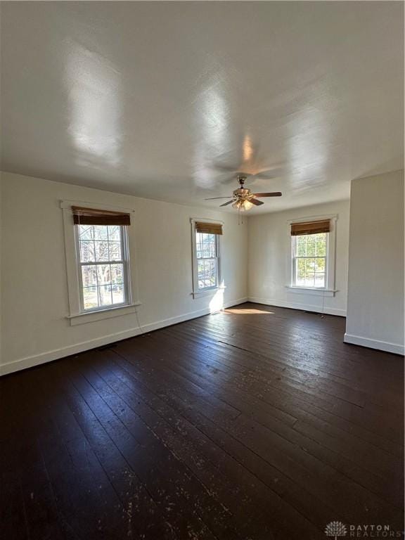 empty room with baseboards, dark wood finished floors, and a wealth of natural light