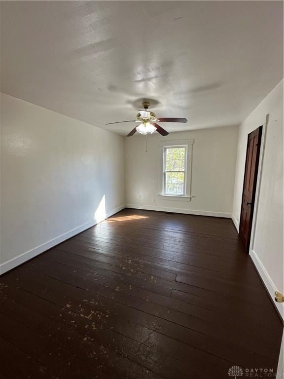 unfurnished room featuring dark wood finished floors, baseboards, and ceiling fan