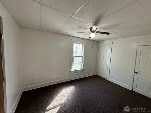 unfurnished bedroom with a ceiling fan, a paneled ceiling, and baseboards