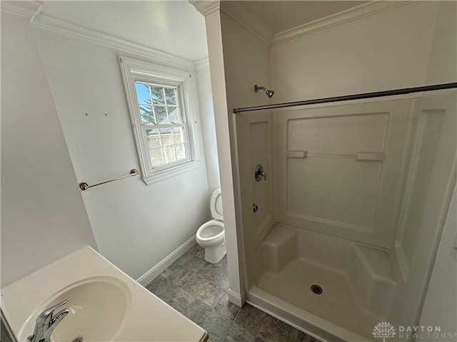 bathroom with baseboards, a shower stall, ornamental molding, and a sink