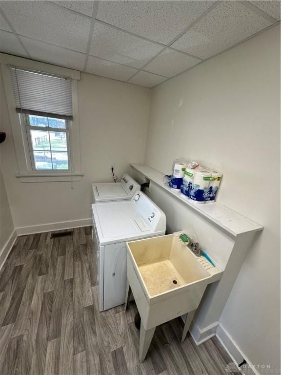 laundry area featuring laundry area, separate washer and dryer, a sink, wood finished floors, and baseboards