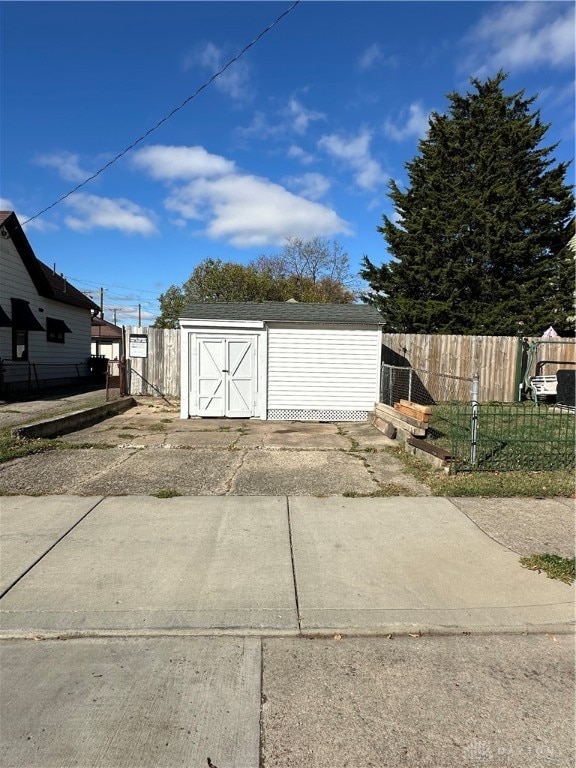 garage with concrete driveway, fence, and a storage unit