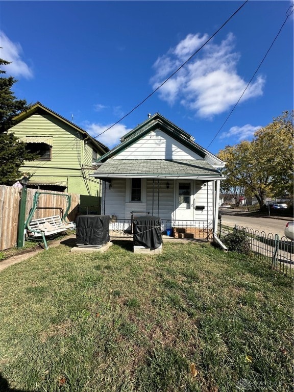 rear view of house featuring fence, a porch, and a yard