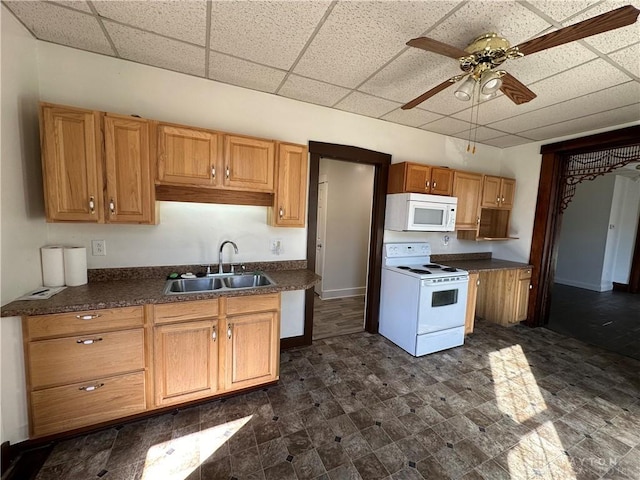 kitchen featuring dark countertops, a paneled ceiling, a sink, ceiling fan, and white appliances