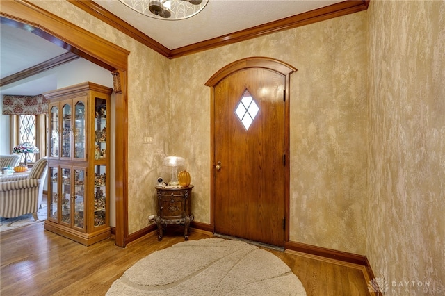 entryway with wood-type flooring and crown molding