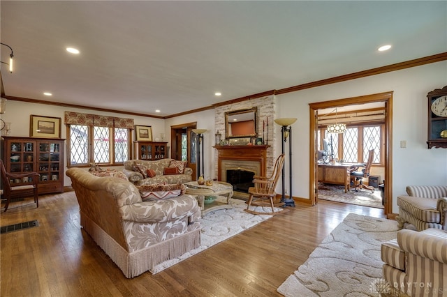 living room featuring a fireplace, hardwood / wood-style flooring, a healthy amount of sunlight, and crown molding