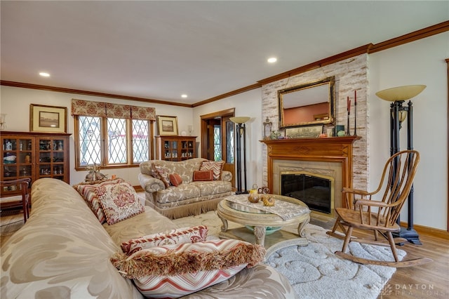 living room with ornamental molding, light wood-type flooring, and a large fireplace