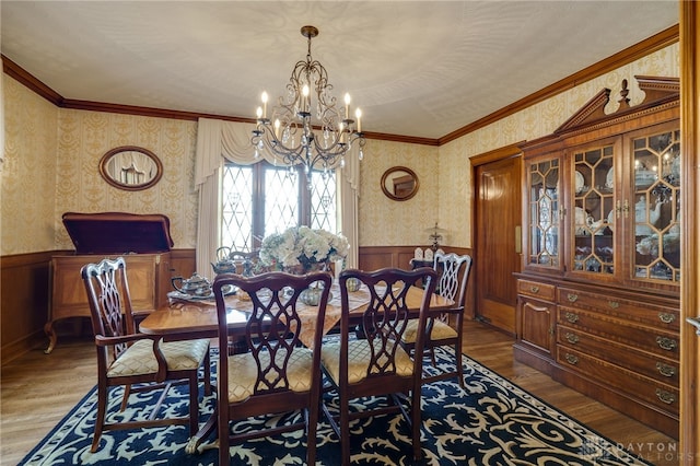 dining space with ornamental molding, hardwood / wood-style flooring, and an inviting chandelier