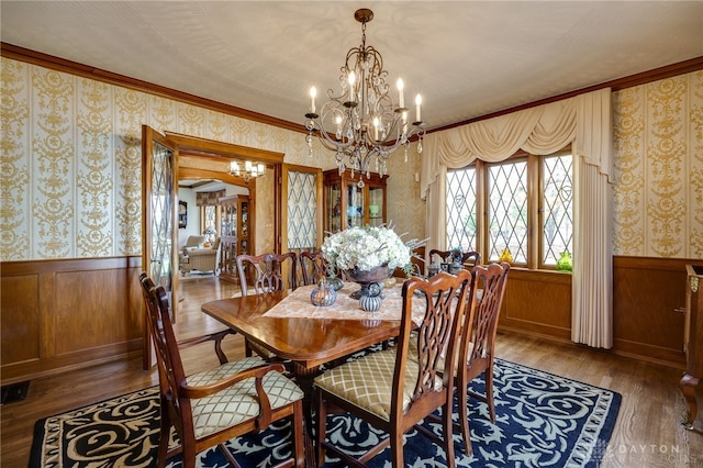 dining space featuring ornamental molding, wood walls, hardwood / wood-style flooring, and an inviting chandelier