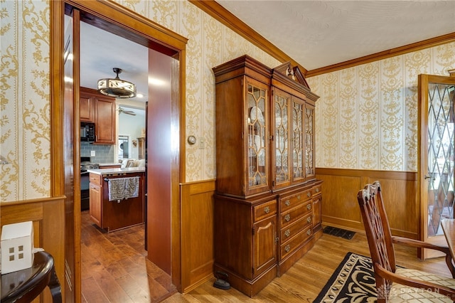 hall featuring ornamental molding, wood-type flooring, and wood walls