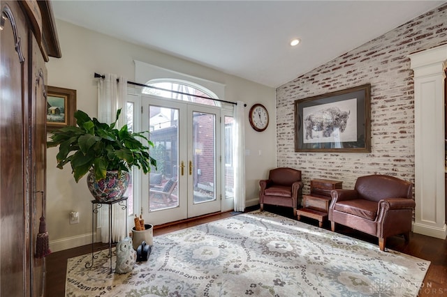 sitting room with ornate columns, french doors, dark hardwood / wood-style flooring, and vaulted ceiling