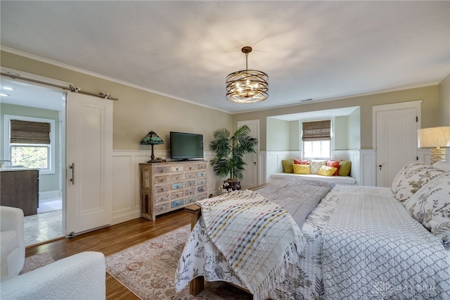 bedroom featuring a chandelier, multiple windows, a barn door, and hardwood / wood-style flooring