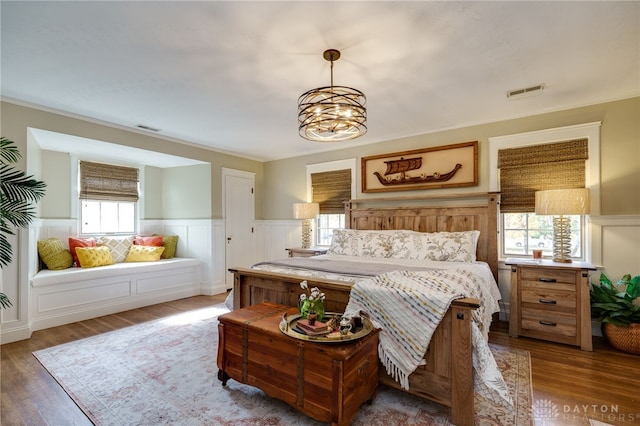 bedroom featuring wood-type flooring, multiple windows, and a chandelier