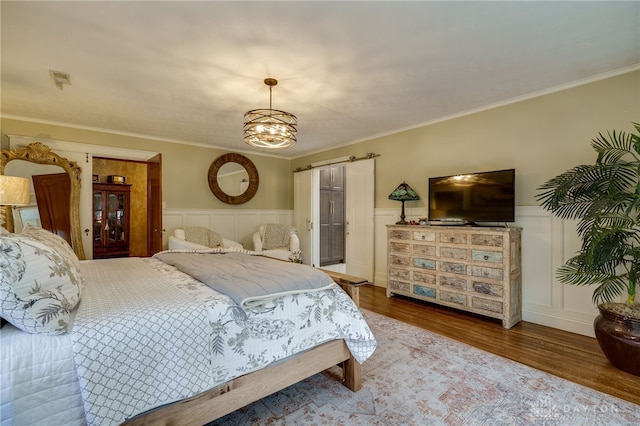 bedroom featuring hardwood / wood-style floors, a chandelier, and crown molding