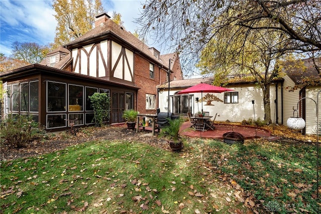 back of house featuring a lawn, a sunroom, and a patio