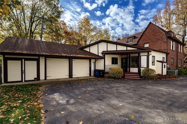 view of front of house featuring a garage, cooling unit, and covered porch