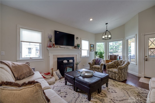 living room featuring hardwood / wood-style floors, a wealth of natural light, a notable chandelier, and vaulted ceiling