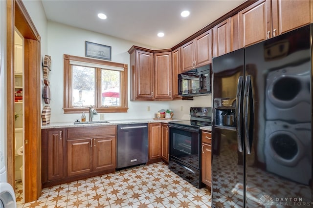 kitchen featuring black appliances, light stone countertops, and sink