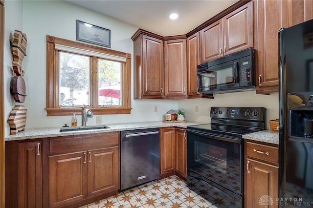 kitchen with black appliances, light stone countertops, and sink