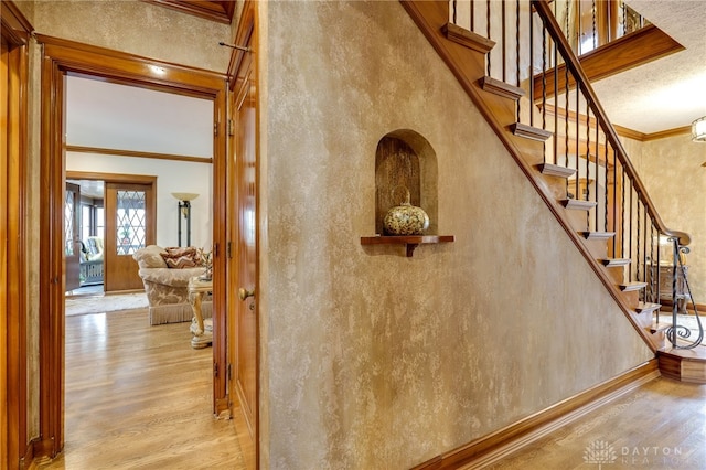 stairs with hardwood / wood-style floors and crown molding