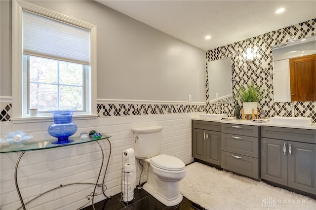 bathroom with toilet, vanity, and tile walls