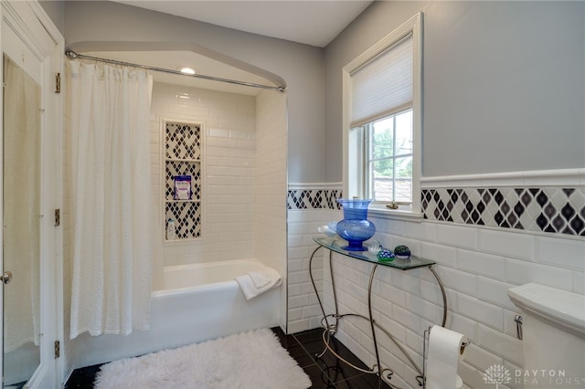 bathroom with tile patterned floors, shower / bath combo, tile walls, and toilet