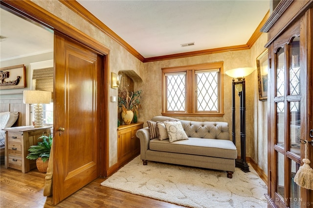 sitting room with ornamental molding and light wood-type flooring