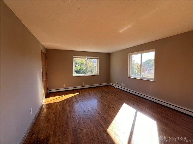 empty room featuring a baseboard heating unit and dark hardwood / wood-style flooring