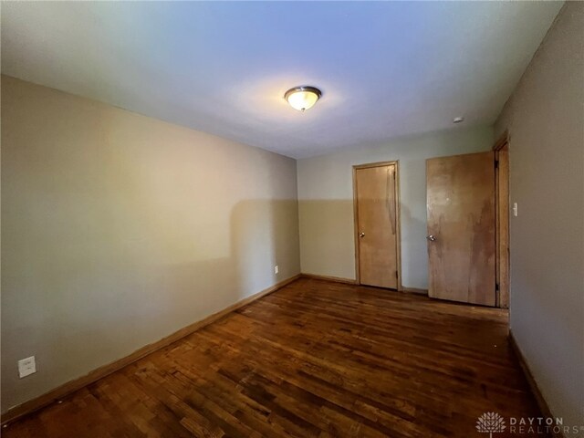 unfurnished room with dark wood-type flooring